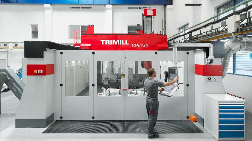 CNC Zerspanung - Großbearbeitung bei weba Werkzeugbau großes CNC Bearbeitungszentrum der Marke Trimill VM6535 wird von einem Zerspanungstechniker auf der Steuerungskonsole programmiert, um anschließend CNC Zerspanung durchzuführen