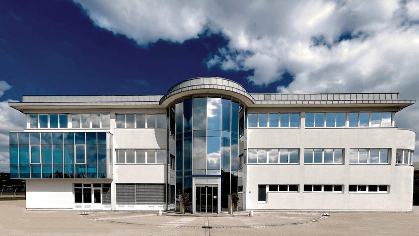 Expertise in der Umformtechnik - Entwicklungszentrale weba in Dietach Außenaufnahme des Verwaltungstraktes der Entwicklungszentrale von weba in Dietach unter einem blauen Himmel mit Wolken.