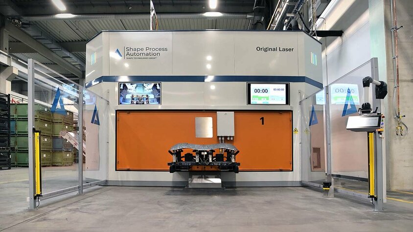 Moderne Laserschneidanlage für präzises Laserschneiden von 3D Metallbauteilen Eine Laserschneidanlage der Firma Shape Process Automation, ausgestattet mit zwei Monitoren, die eine moderne und technologisch fortgeschrittene Qualitätskontrolle ermöglichen, umgeben von der robusten und präzisen Maschinerie der Schneidanlage.