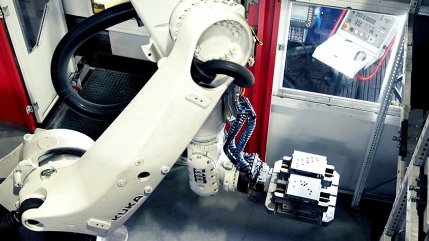 weba Werkzeugbau - Automatisierung in der Zerspanung Ein Roboterarm eines automatisierten 5-Achs Bearbeitungszentrums für Einzelteilfertigung entnimmt Stahlblöcke aus dem Palettenwechsler.