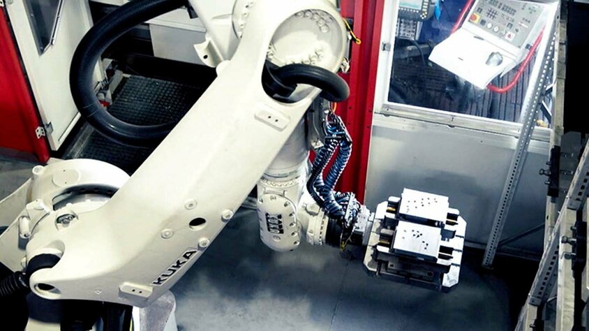weba Werkzeugbau - Automatisierung in der Zerspanung Ein Roboterarm eines automatisierten 5-Achs Bearbeitungszentrums für Einzelteilfertigung entnimmt Stahlblöcke aus dem Palettenwechsler.