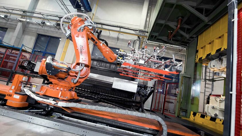 Presshärten - Kammerofentechnologie im Einsatz Roboterarme transferieren vier glühende Platinen von einem Kammerofen in ein Werkzeug für das Presshärten