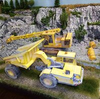 Detailed miniature scene featuring yellow construction machinery set against a rocky landscape.
