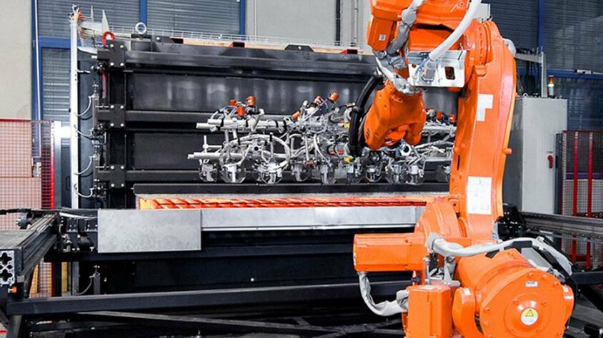 weba Werkzeugbau - Automatisierung des Warmumformprozesses Ein Roboterarm entnimmt vier glühende Formplatinen aus einem Kammer-Warmformofen für den Transfer in die Umformpresse und Bauteilproduktion.