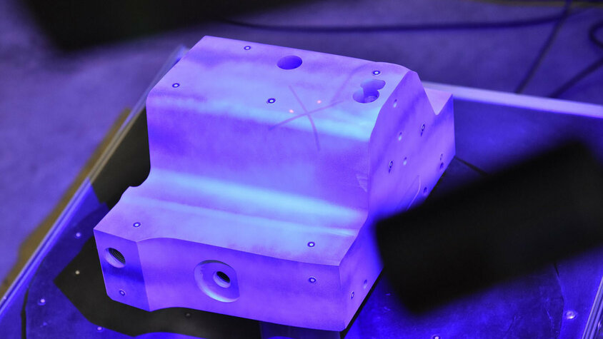 Digitalisierung - Qualitätssicherung im Werkzeugbau Ein Stahleinsatz befindet sich zentriert auf einer Drehscheibe in einem technischen Labor. Ein 3D-Scanner, der über der Drehscheibe positioniert ist, digitalisiert und analysiert das Objekt sorgfältig. Dies verdeutlicht die Digitalisieungs-Initiative von weba in der Qualitätssicherung.
