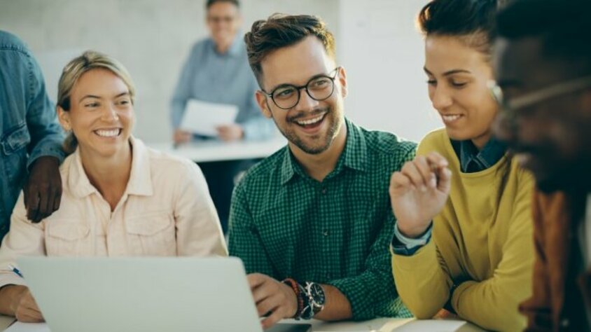 Praktikum Jobs in Steyr - Ferialjobs bei weba Werkzeugbau Fröhlicher Student hat Spaß beim Benutzen eines Laptops mit seinen Freunden im Klassenzimmer. Das Bild symbolisiert Praktikum Jobs in Steyr für Schüler und Studenten bei weba Werkzeugbau.