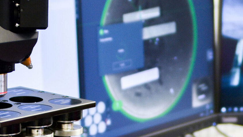 Messtechnik - metallographische Anlaysen Ein Härteprüfgerät für metallographische Analyse in der Messtechnik neben zwei Bildschirmen