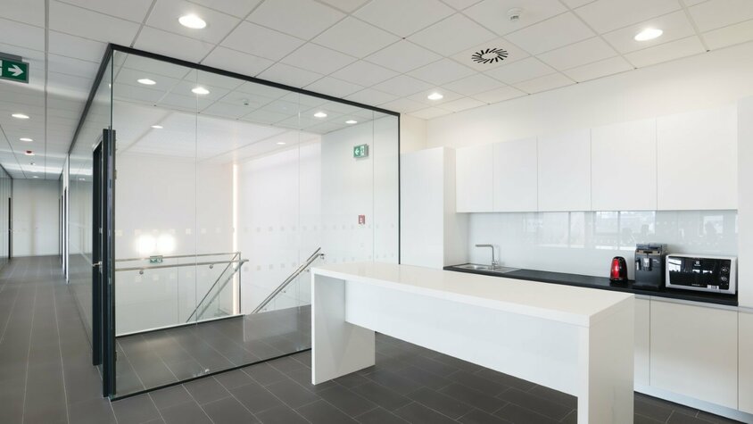 weba Olomouc - Pausenküche für höchste Mitarbeiterzufriedenheit Moderne Pausenküche im weba-Standort Olomouc, in hochglanzweiß gehalten, mit einer einladenden Insel davor.